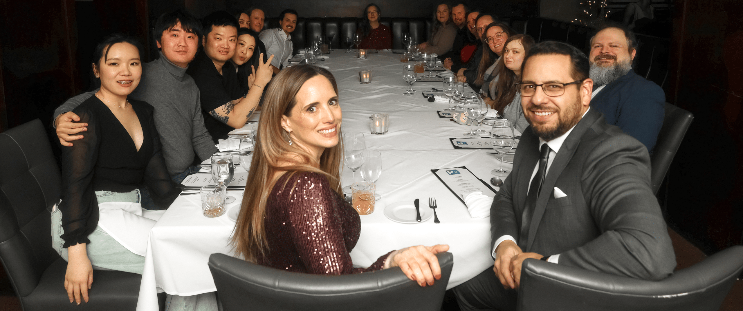 the team members of PCe Solutions sitting at a table during a Christmas party. about