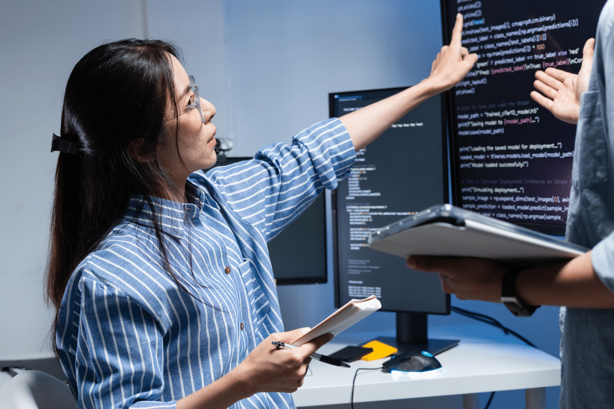 PCe Solutions Calgary managed IT specialist pointing at code on monitors reviewing cybersecurity systems and network infrastructure providing local managed IT services to Calgary businesses across Alberta