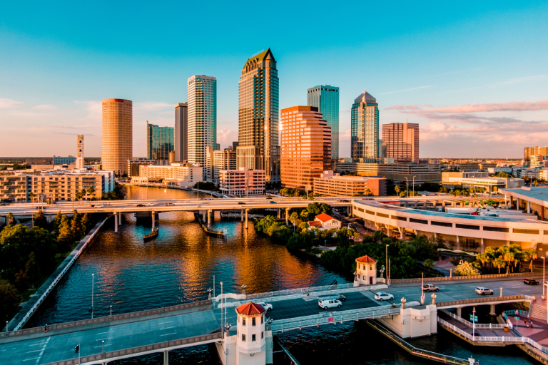 Aerial view of Tampa Florida downtown skyline at golden hour with the Hillsborough River and Kennedy Boulevard bridge in the foreground, served by PCe Solutions local managed IT services and cybersecurity support across the Tampa Bay area